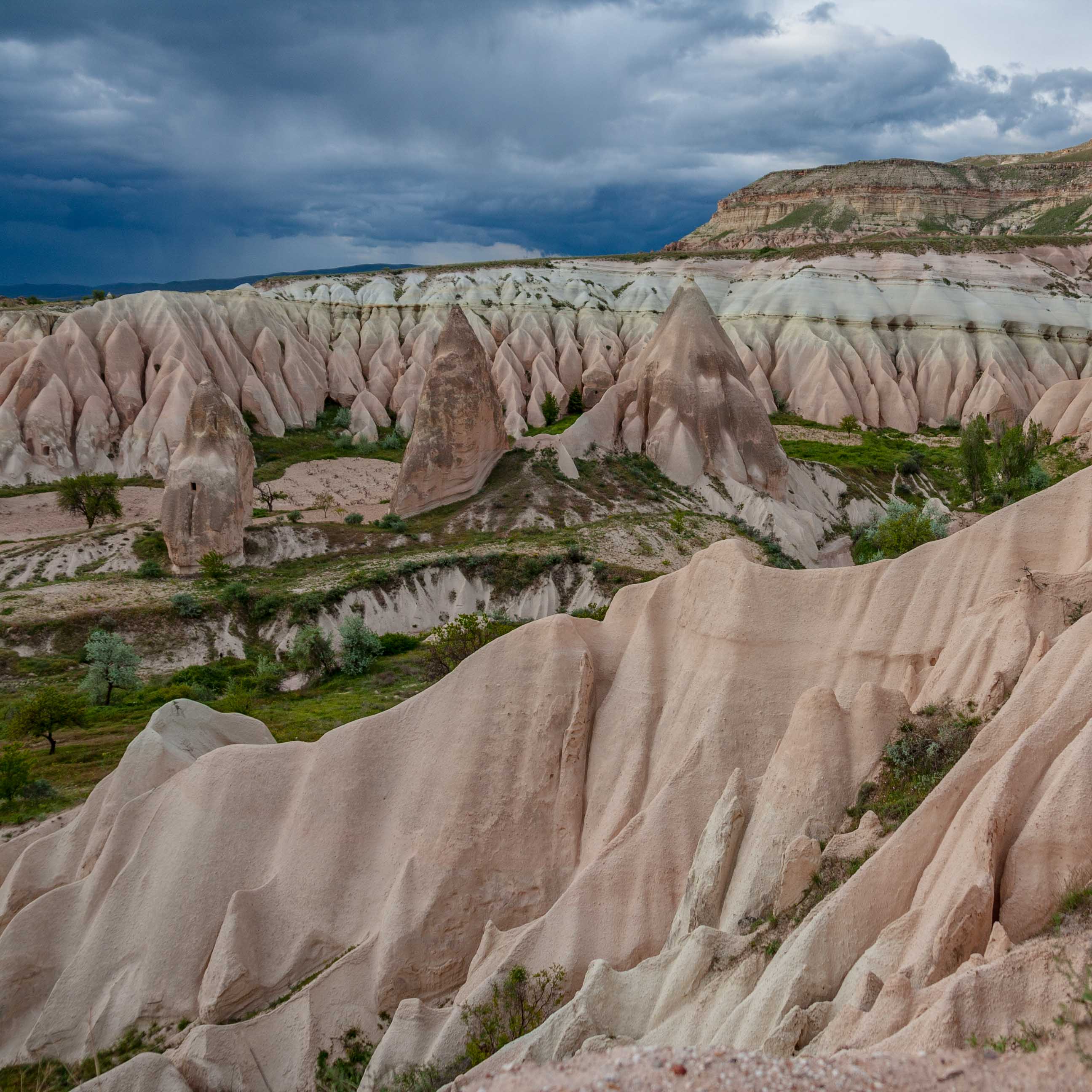 Sand dune shaped formations of Cappadocia on a rainy sky.
